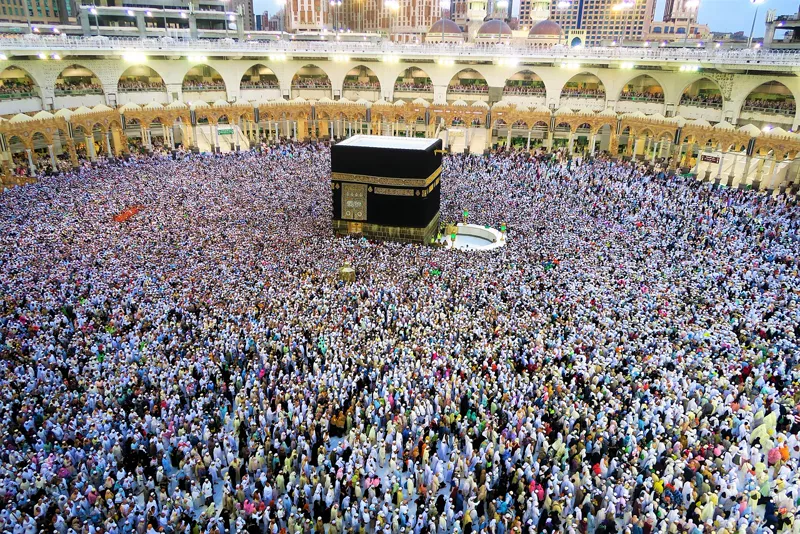 Veduta della Grande Moschea della Mecca illuminata di sera, con la città sullo sfondo