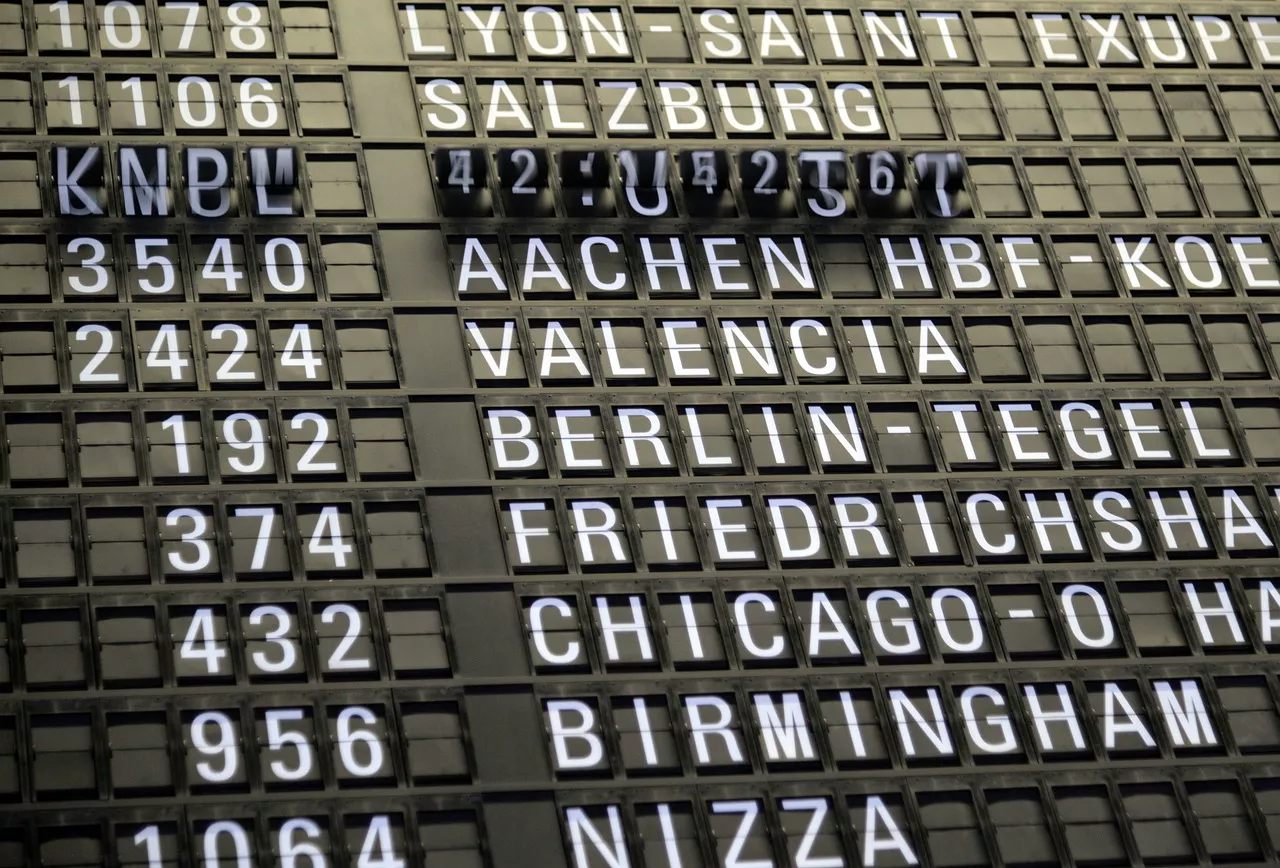 Tabellone delle partenze in aeroporto con indicazioni di voli in ritardo e passeggeri in attesa